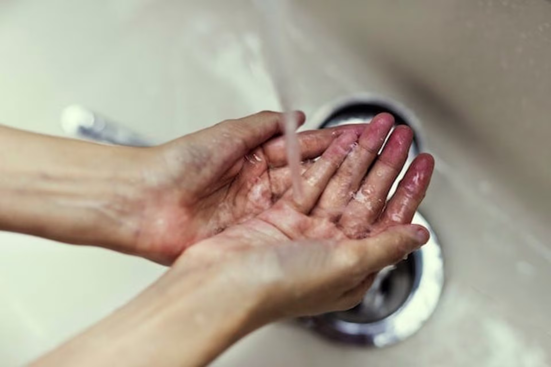 Hands being rinsed under running water at a sink, a simple gesture of self-care encouraged by Roseville therapists to pr