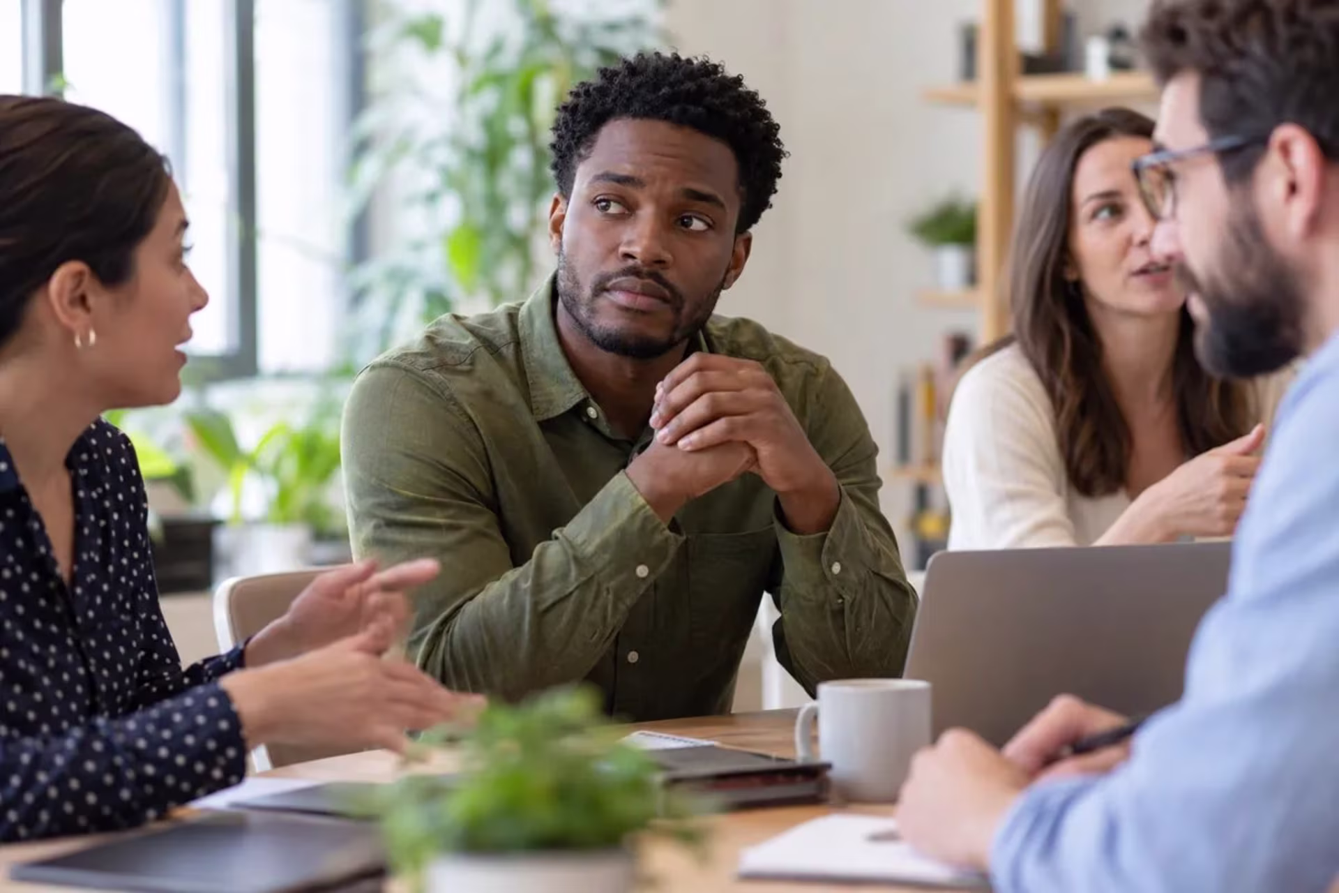 Man experiencing social tension during a small workplace meeting.