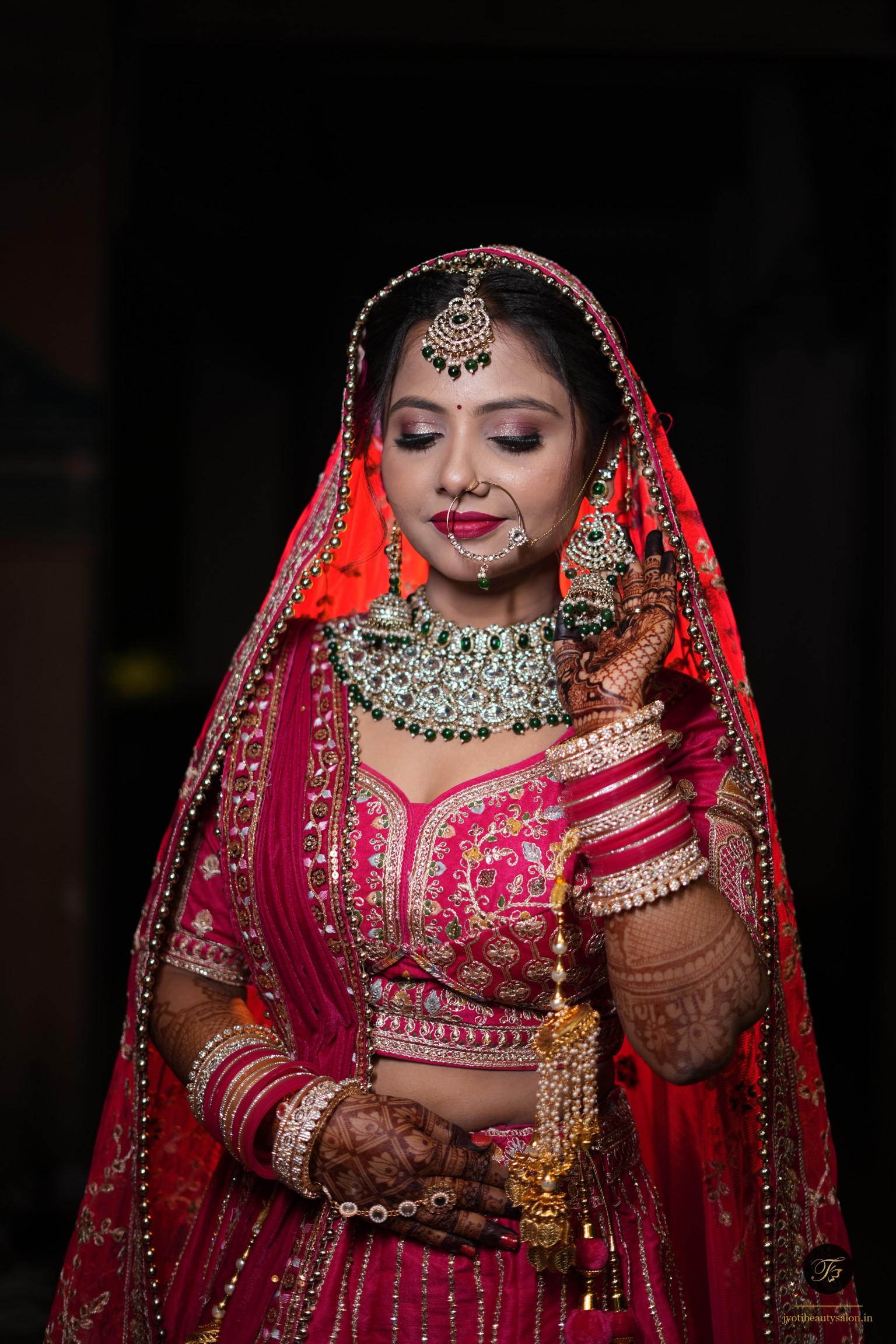 Bridal makeup with heavy emerald choker necklace and crimson magenta silk lehenga at Jyoti Beauty Salon Chapra.