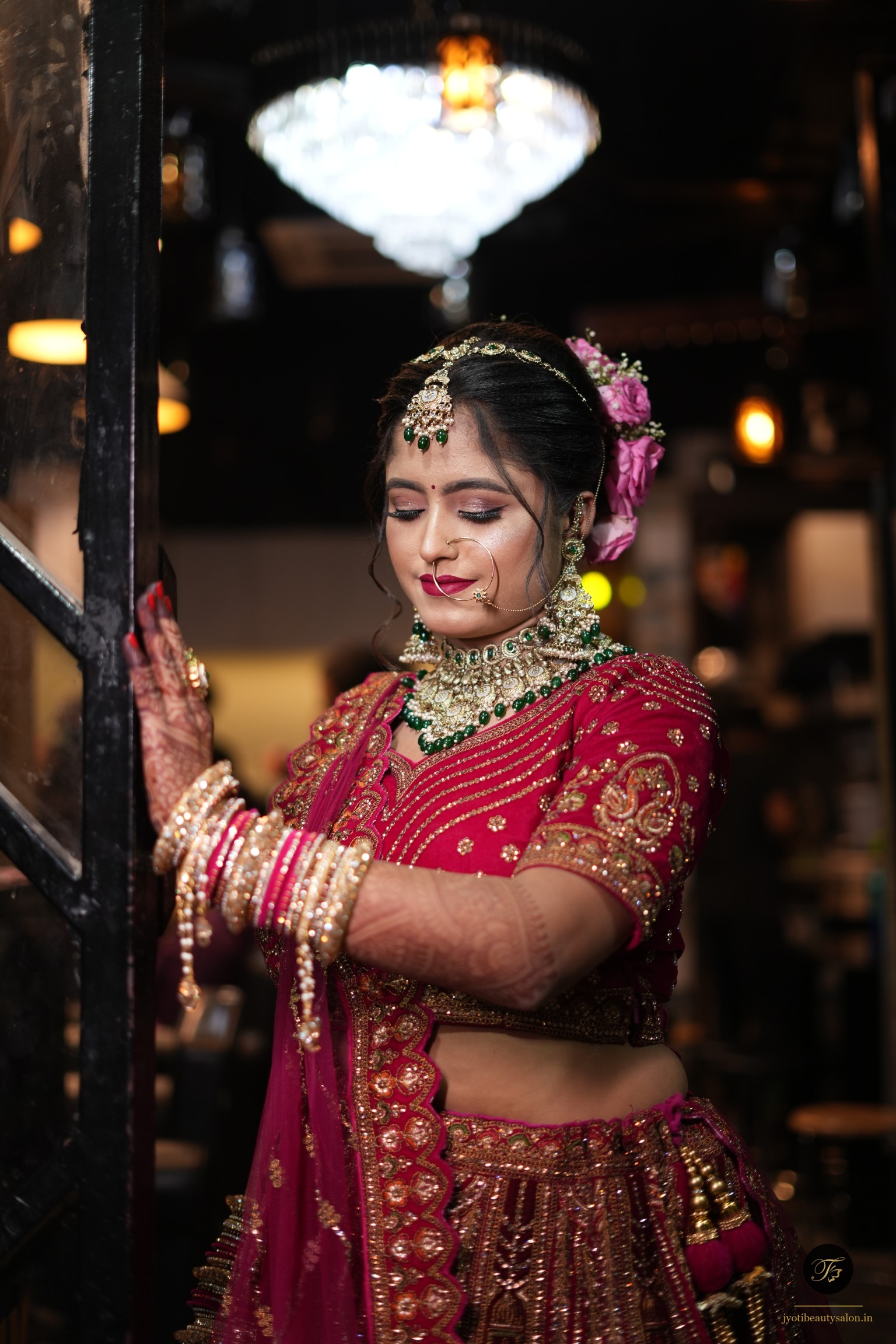 Bridal makeup with magenta lehenga and pink rose hair accessory at Jyoti Beauty Salon Chapra.