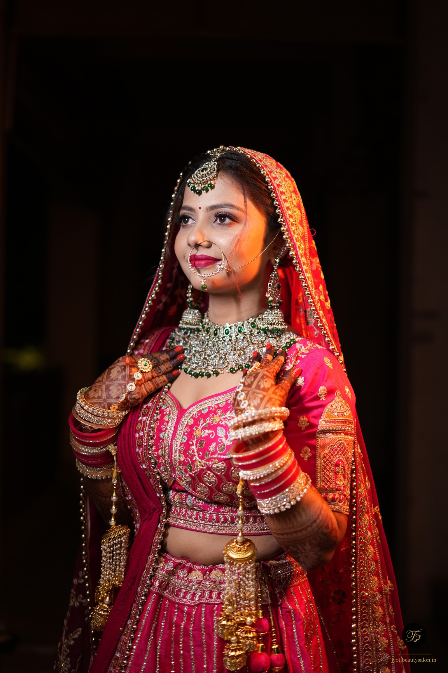 Front-facing bridal makeup look with a heavy emerald choker necklace and bold red lipstick at Jyoti Beauty Salon Chapra.