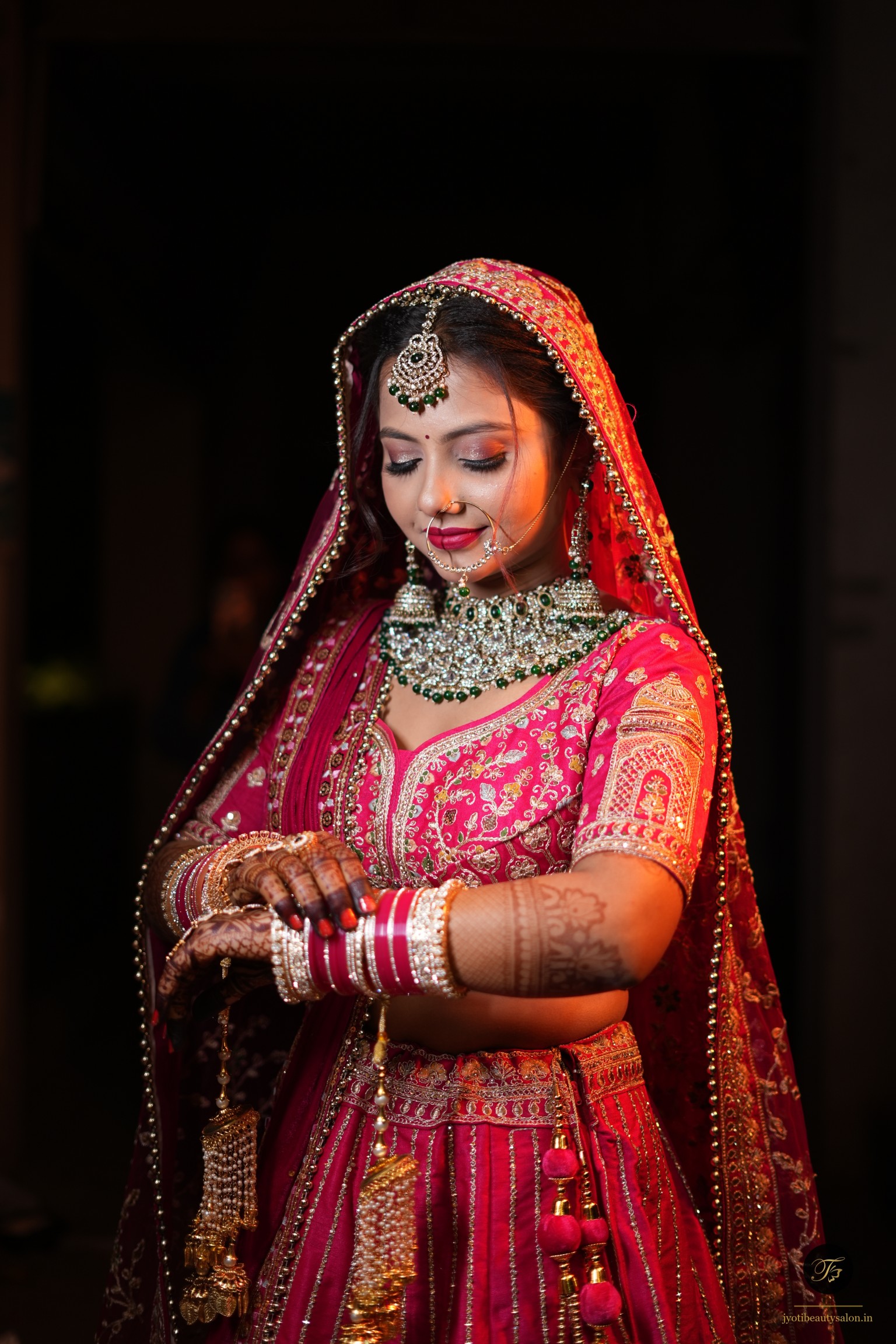 Indian bride in magenta lehenga adjusting her chooda and gold kaleere at Jyoti Beauty Salon in Chapra.