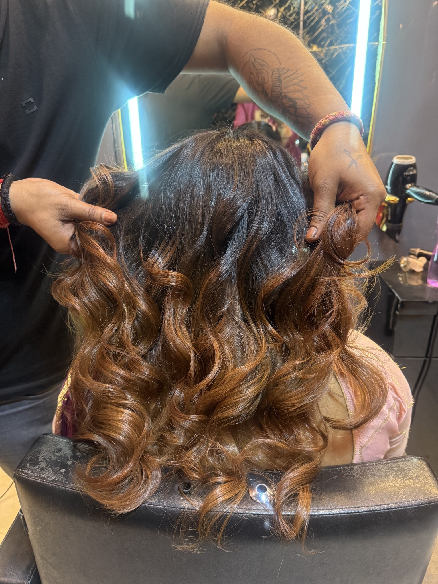 Expert hair styling creating voluminous wavy curls at salon