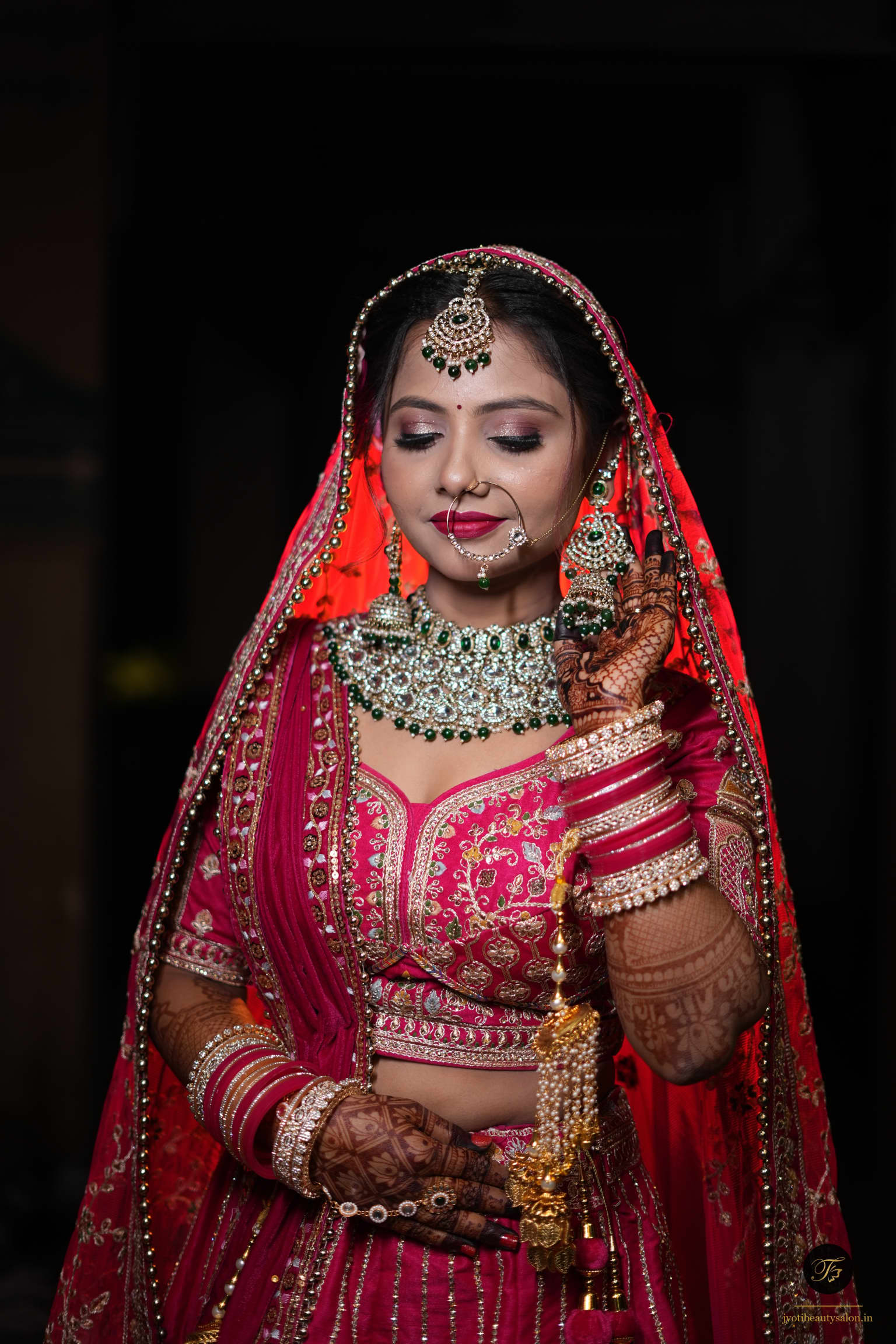 Bridal makeup with heavy emerald choker necklace and crimson magenta silk lehenga at Jyoti Beauty Salon Chapra.