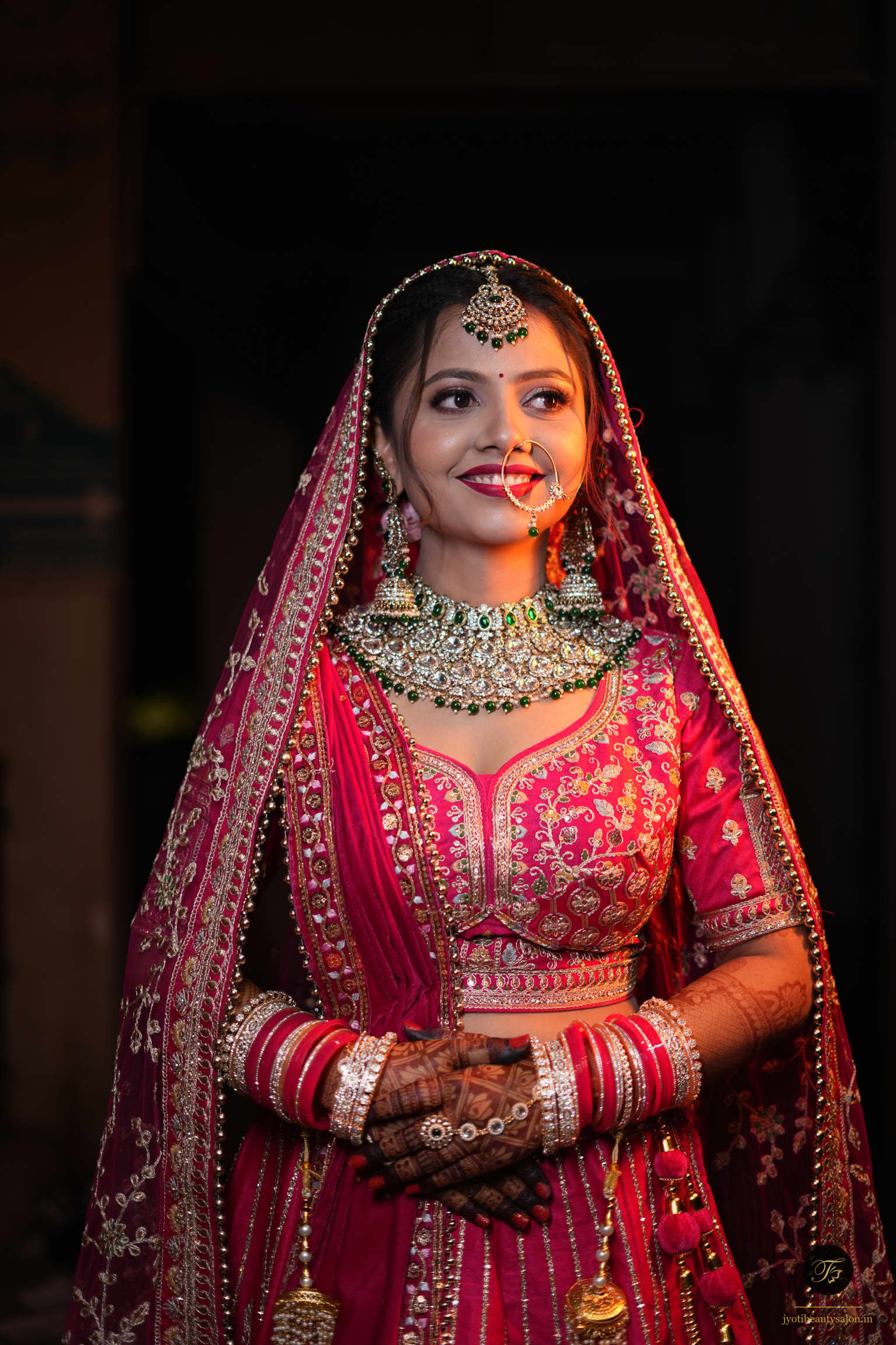 Frontal bridal portrait with heavy emerald jewelry and magenta lehenga at Jyoti Beauty Salon Chapra Bihar.