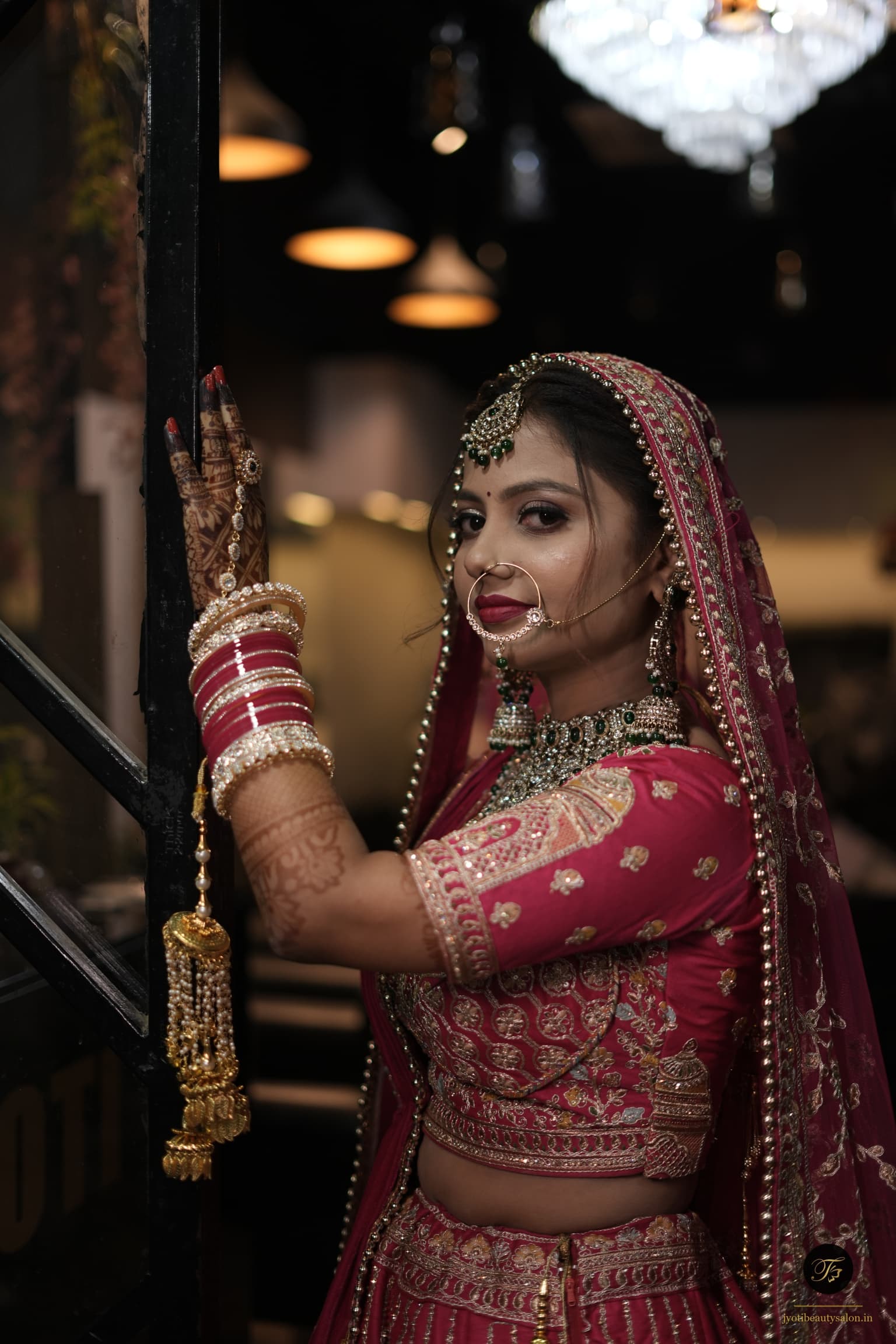 Bridal gold kalire and mehendi details with magenta wedding lehenga by Jyoti Beauty Salon in Chapra.
