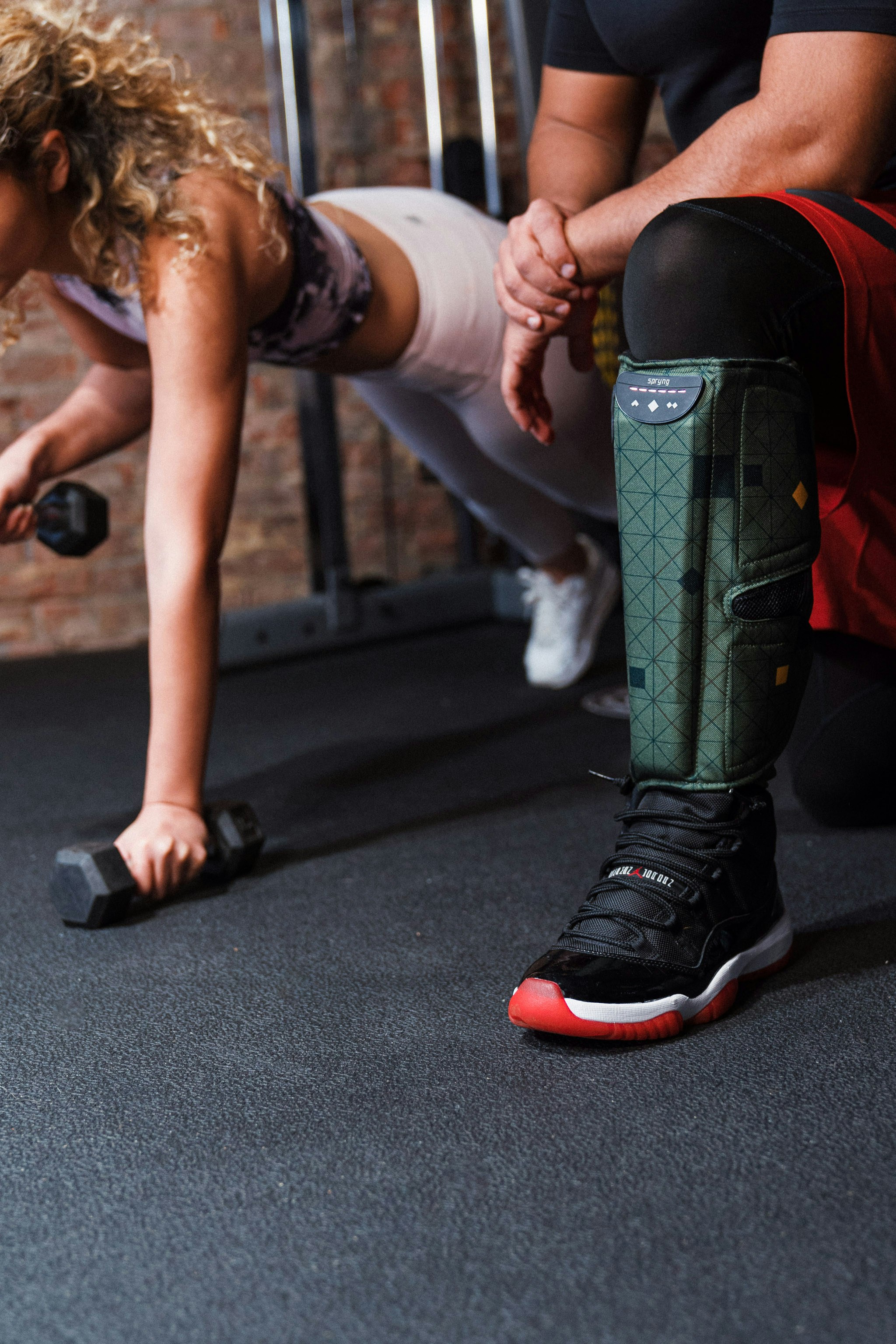 Person using cordless full-leg compression recovery boots while seated at home