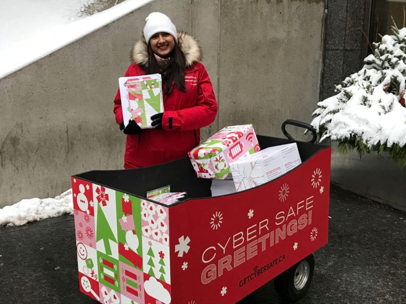 A person with a Get Cyber Safe push wagon filled with branded gift wrapped boxes