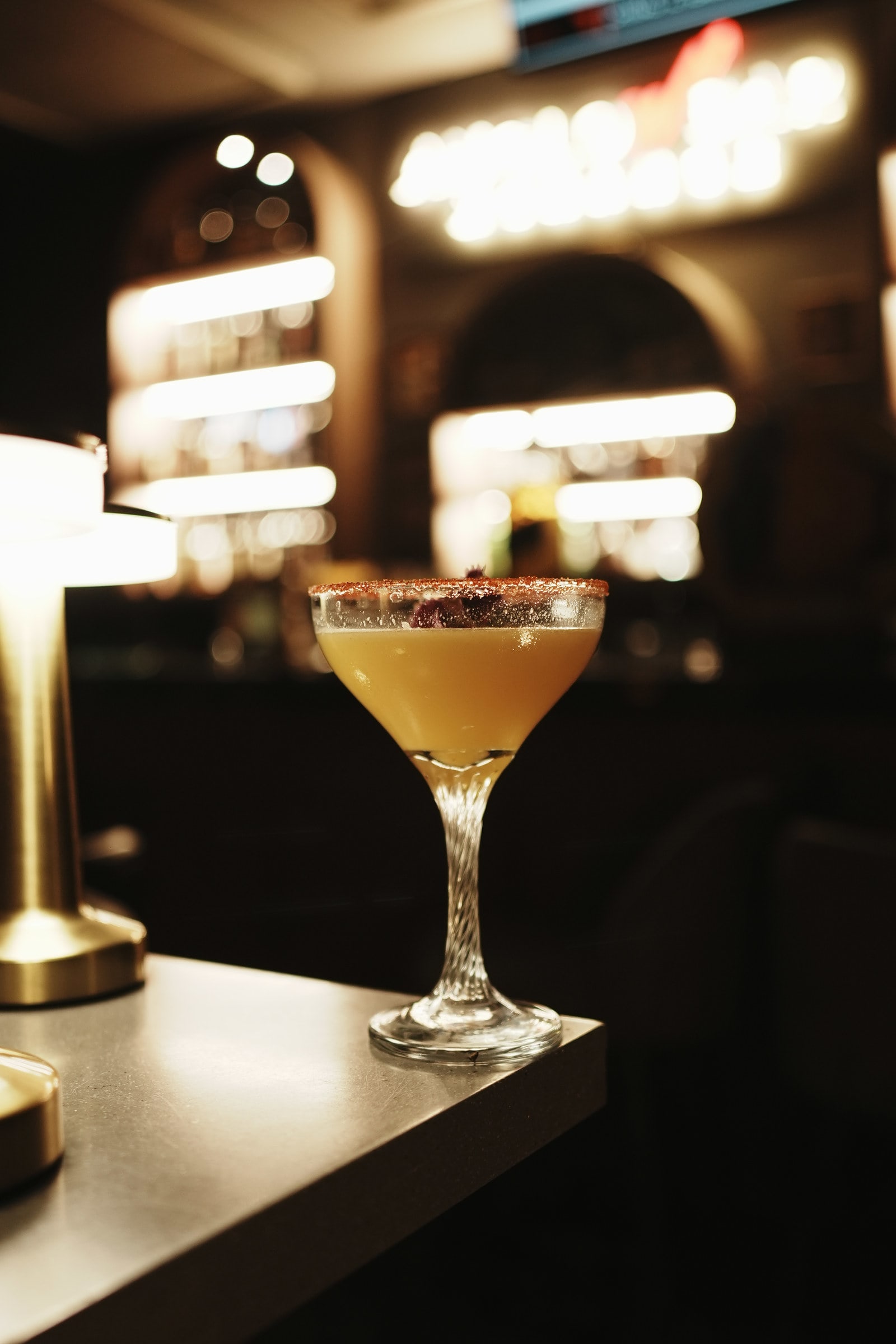 Golden cocktail with a spiced rim on a bar counter