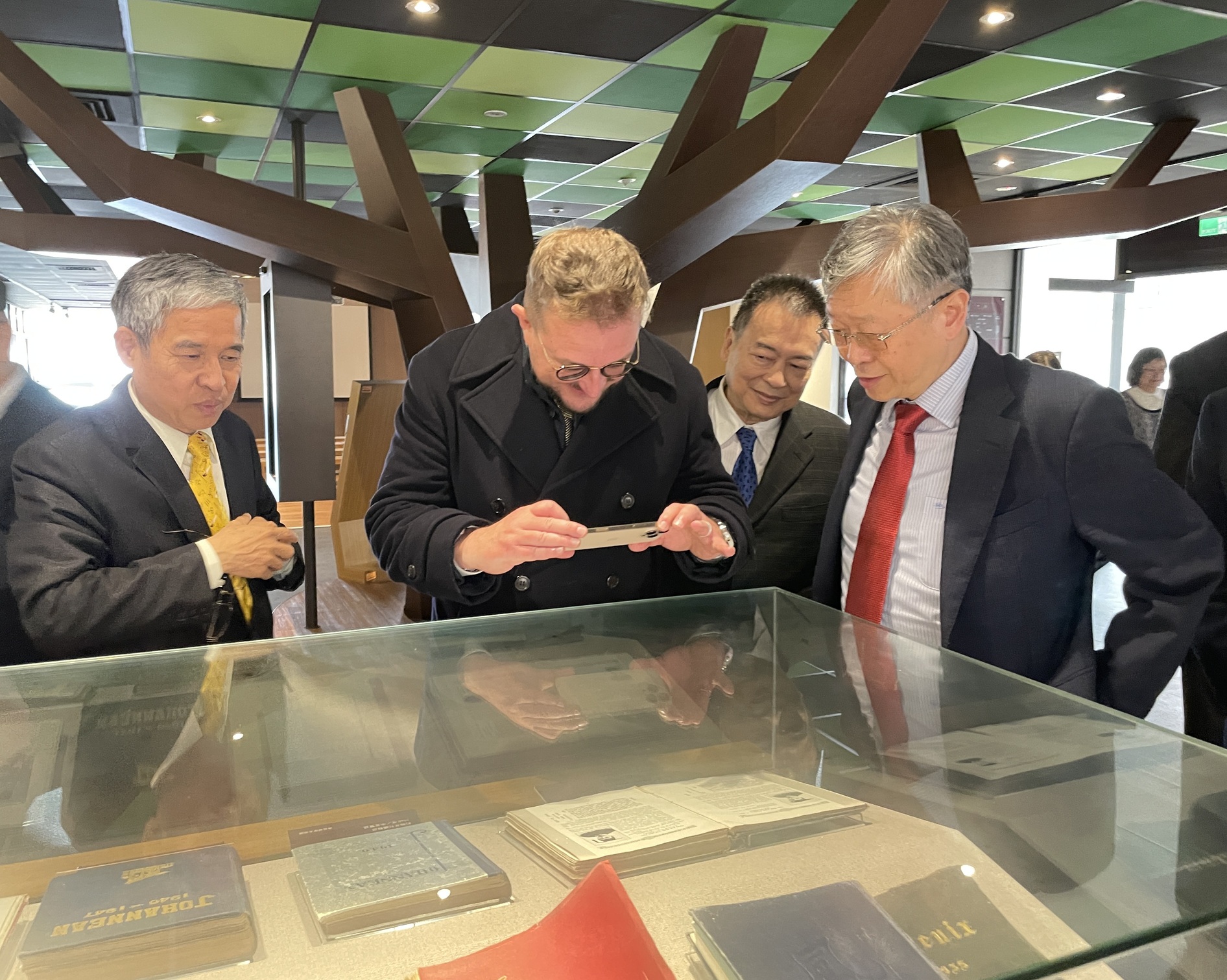 Datavault AI主席暨執行長Nathaniel Bradley參觀上海聖約翰大學校史典藏暨研究中心，拿起手機對著曾任中華民國第5任總統的約大校友嚴家淦展示資料拍攝留念。(聖約翰科技大學提供)