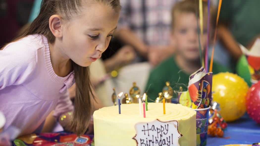 Girl blowing out birthday candles on cake.