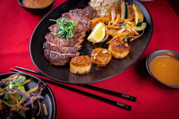 A spread of food from EAST, featuring several plates and chopsticks.