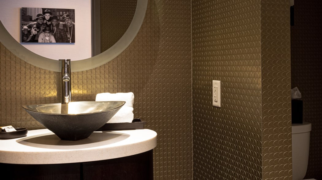 a bathroom with a basin sink and small round penny tiles on the wall