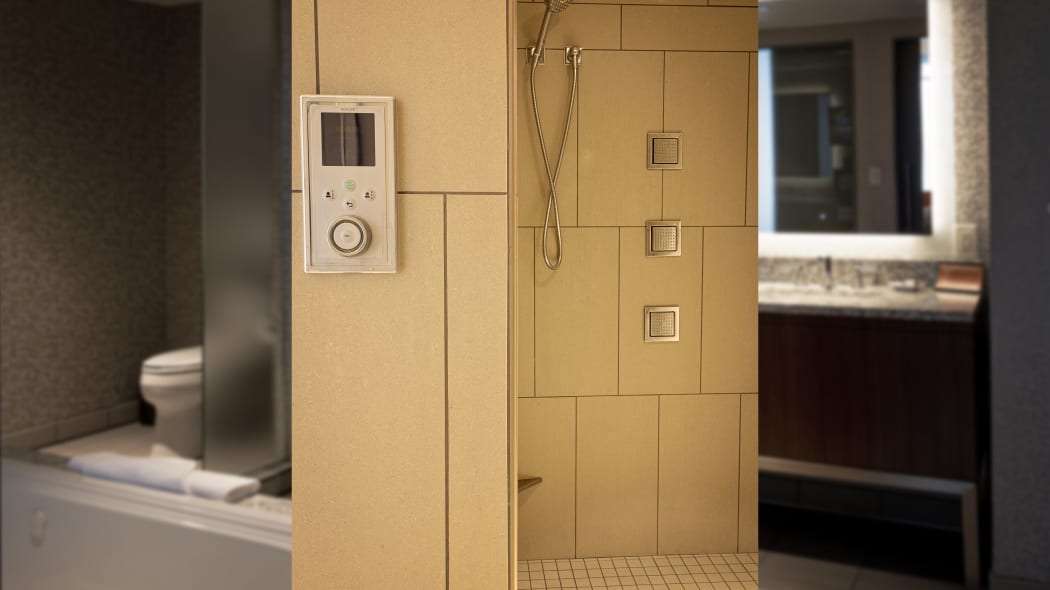 a luxuriously tiled shower featuring 3 wall-mounted jets in addition to a handheld sprayer above head height