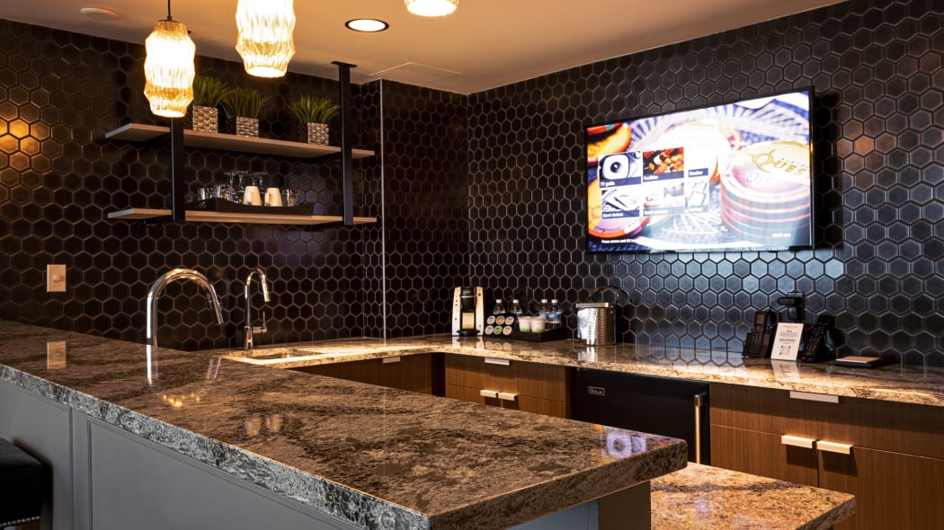 the kitchen area of the suite has nice counters and tiles, with a tv mounted on the wall