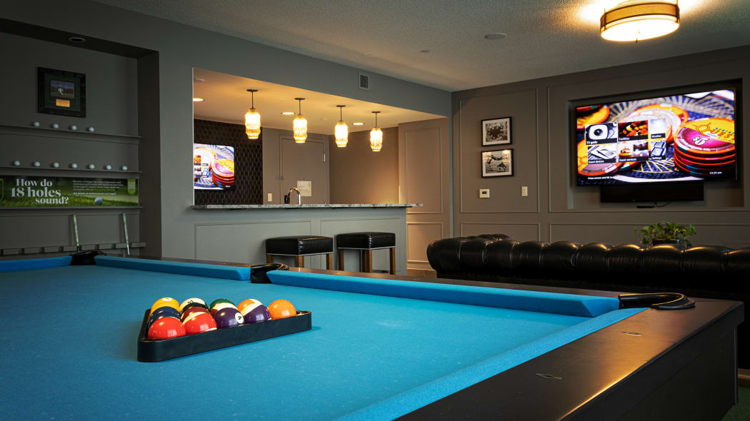 a view of the billiards table with a large tv mounted on the wall behind it