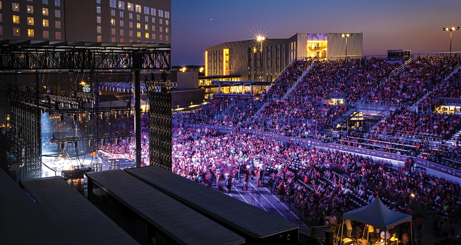 A photo of the crowd enjoying a show at BECU Live. They're bathed in pink and purple light emanating from the stage.