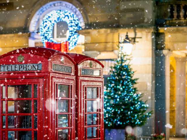 Cabines telefonicas vermelhas classicas com neve caindo em frente ao natal