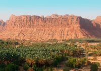 Sunset over abandoned mud houses and oasis along alulas desert mountains