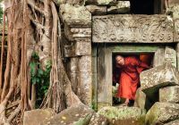 Monge explorando as ruínas de  templo no Camboja