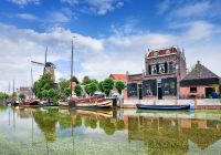 Canal verde e sereno com barcos atracados e casa monumentais na cidade velha de gouda na holanda