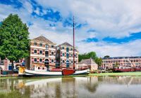 Gouda holanda antiga mansao renovada com um barco branco atracado refletido no canal
