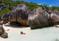 Raffles seychelles casal sentado mar pedras