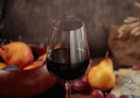 Glass of red wine served with blue cheese on dark wooden background