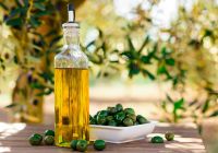 Still life with green olives and oil on table in olive grove