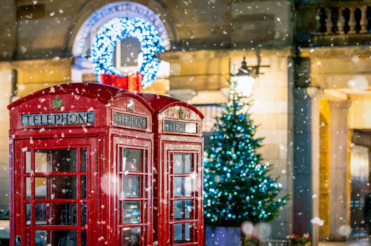 Cabines telefonicas vermelhas classicas com neve caindo em frente ao natal
