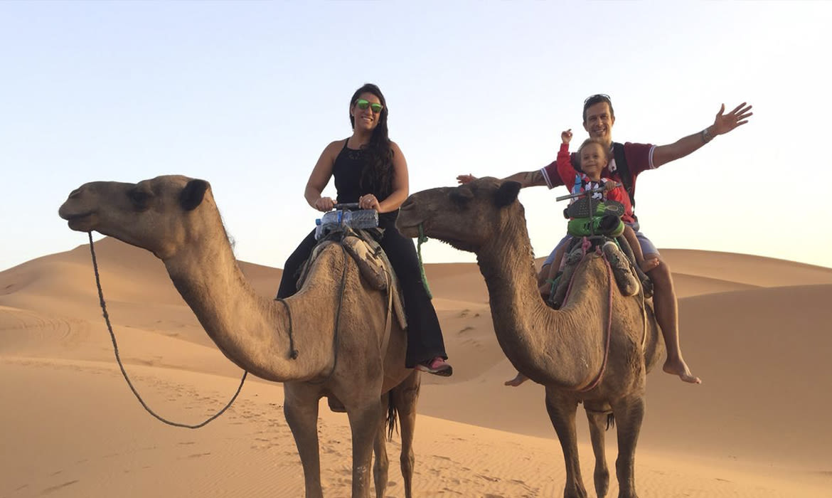 Passeio de camelo em Dubai. Dunas ao fundo A esquerda - Rita montada sob camelo A direta - Ronaldo e Romeo fazem pose para a foto.