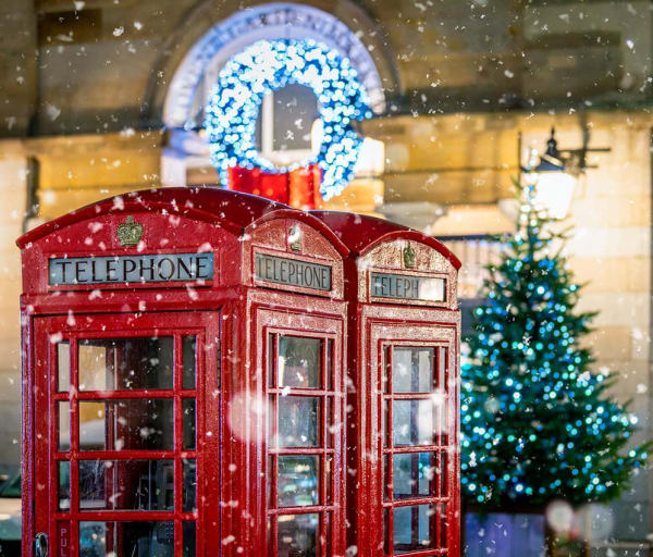Cabines telefonicas vermelhas classicas com neve caindo em frente ao natal