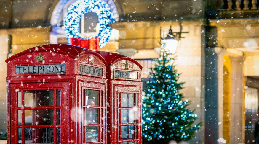 Cabines telefonicas vermelhas classicas com neve caindo em frente ao natal