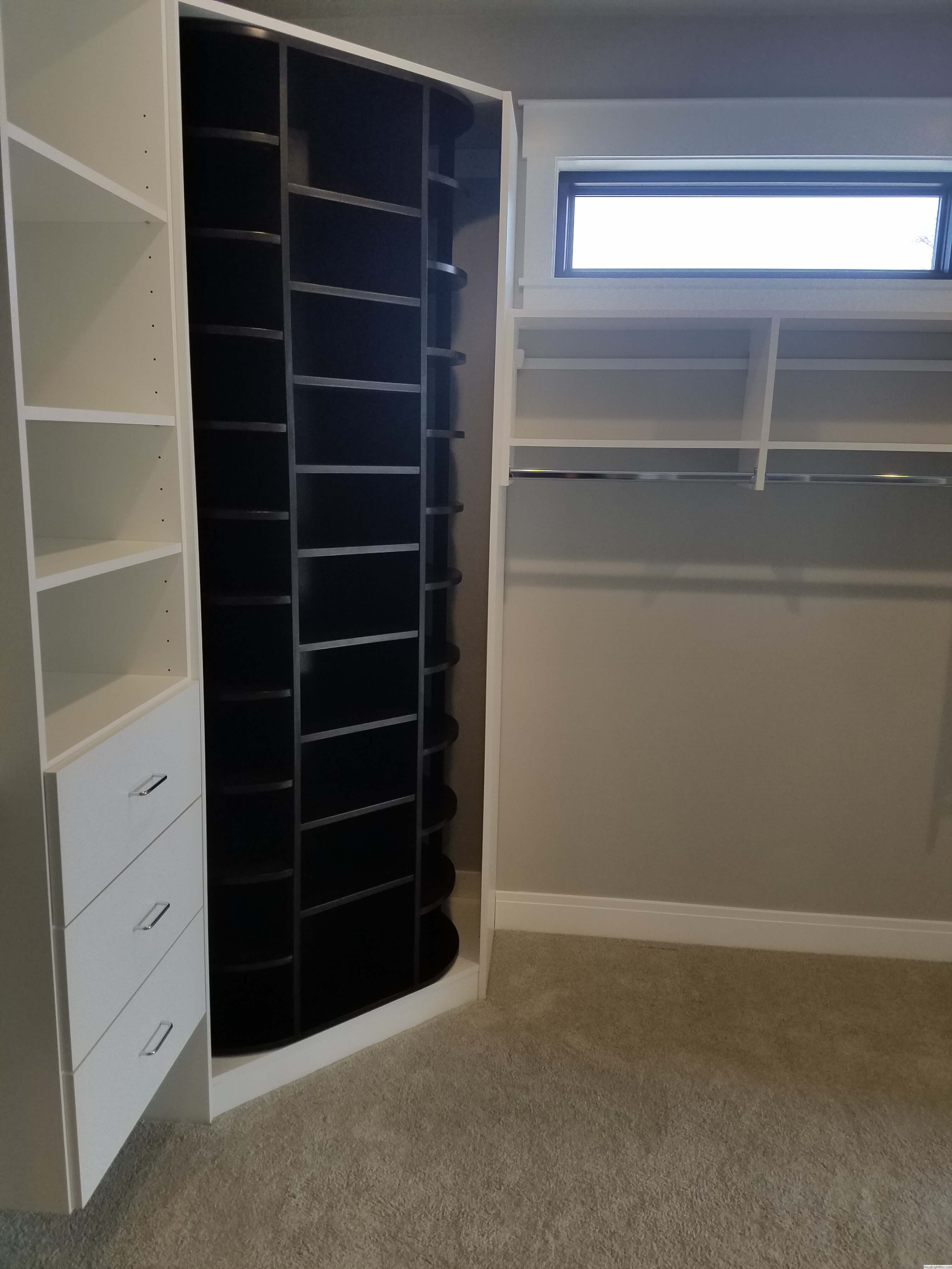 Closet system with black curved corner shelves, drawers, and window lighting in Green Bay, WI.