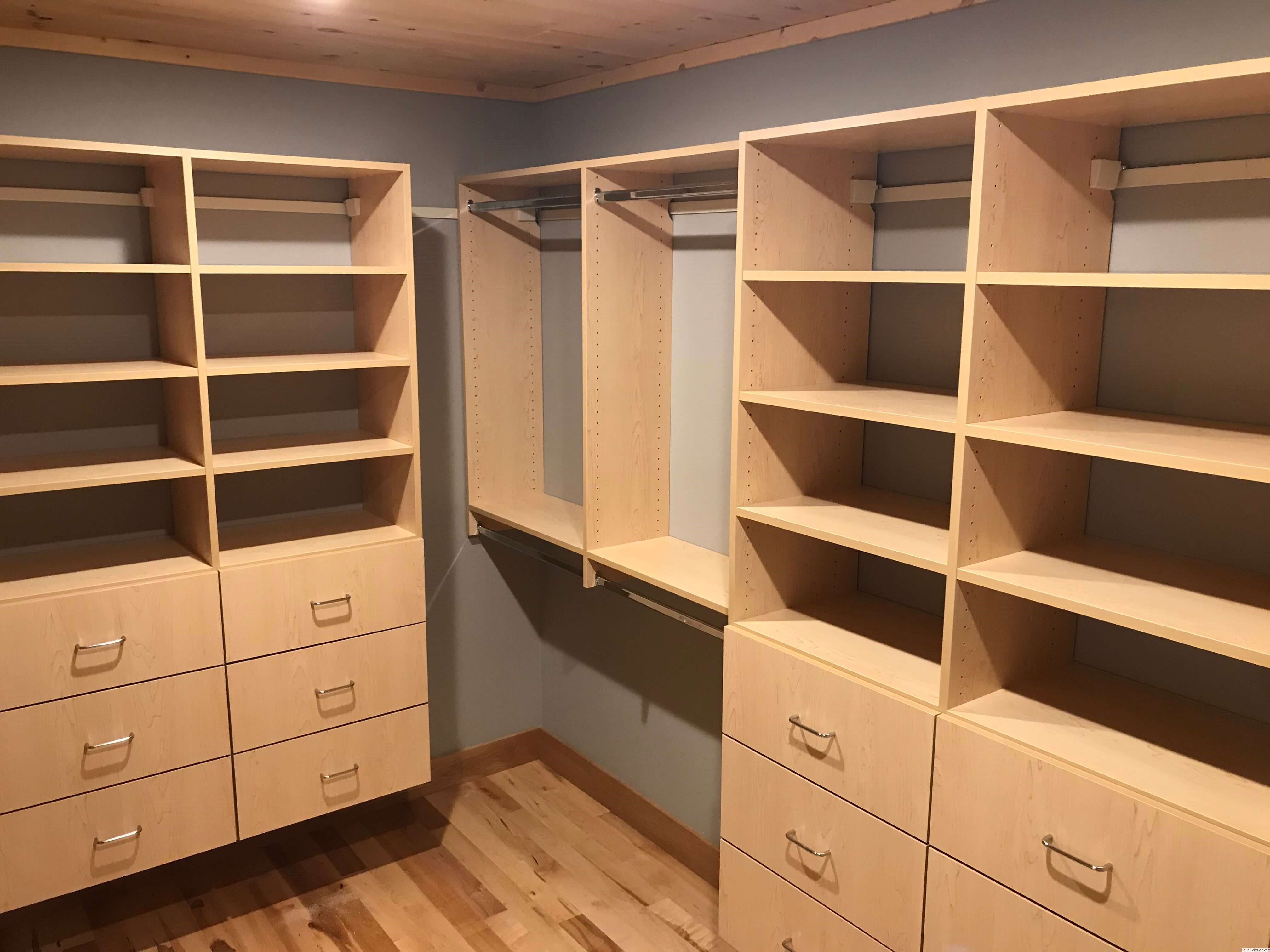 Custom closet with light wood drawers, open shelving, and double hanging rods in Green Bay, WI.