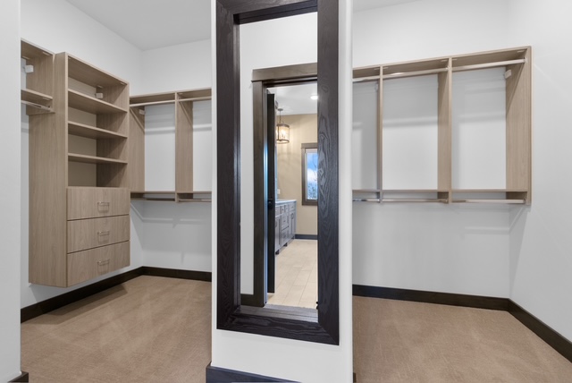 Custom closet with natural wood shelving, built-in drawers, and full-length mirror in Green Bay, WI.