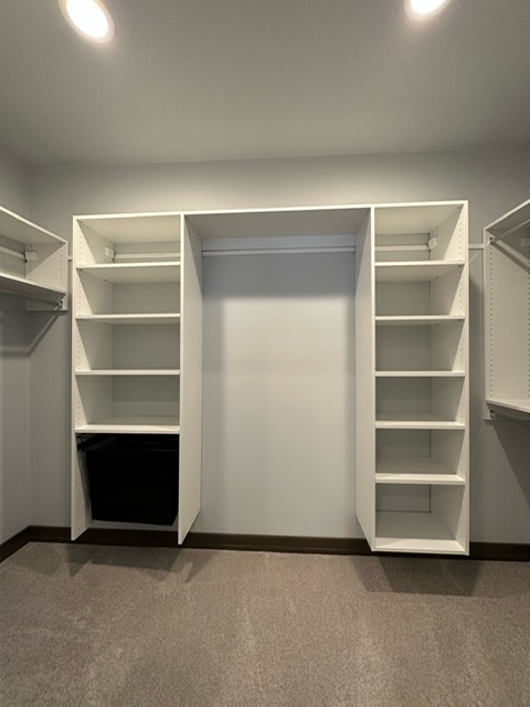 Custom walk-in closet with built-in drawers, open shelving, and pull-down hanging rods in Green Bay, WI.