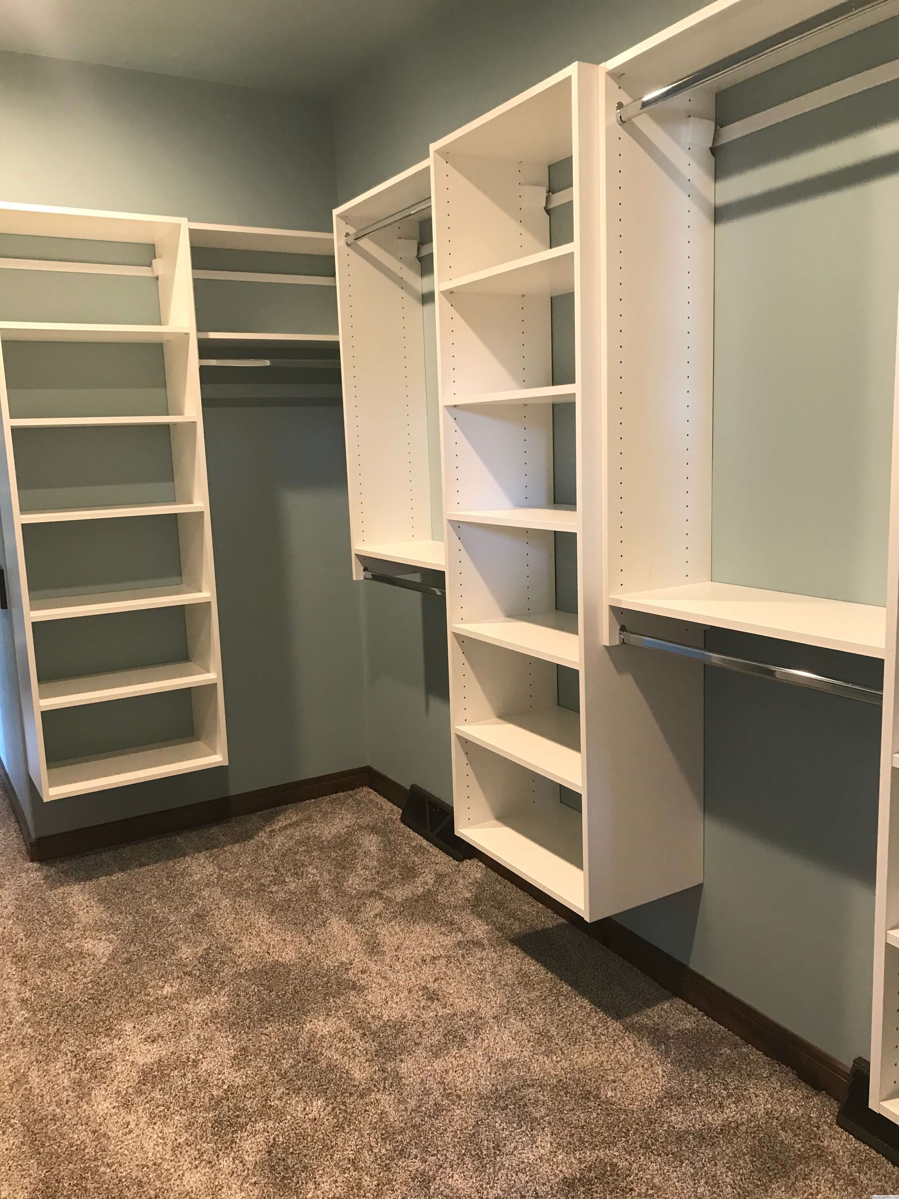 Custom closet with staggered white shelving and open hanging space in Green Bay, WI.