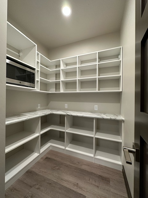 Custom pantry with white open shelving, marble-look countertops, and built-in microwave in Green Bay, WI.