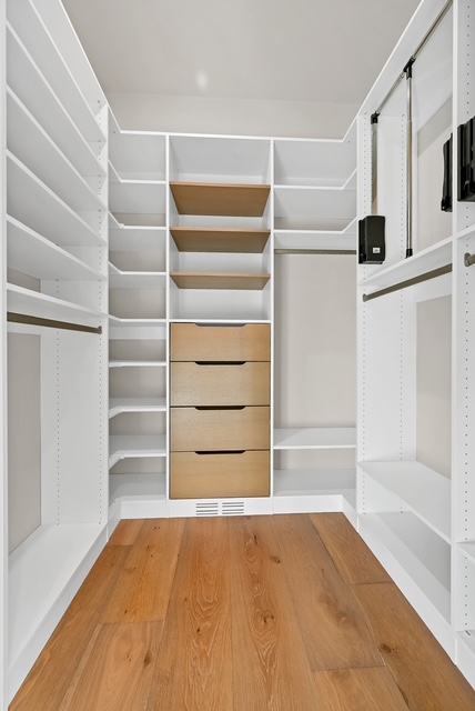 Custom walk-in closet with built-in drawers, open shelving, and pull-down hanging rods in Green Bay, WI.
