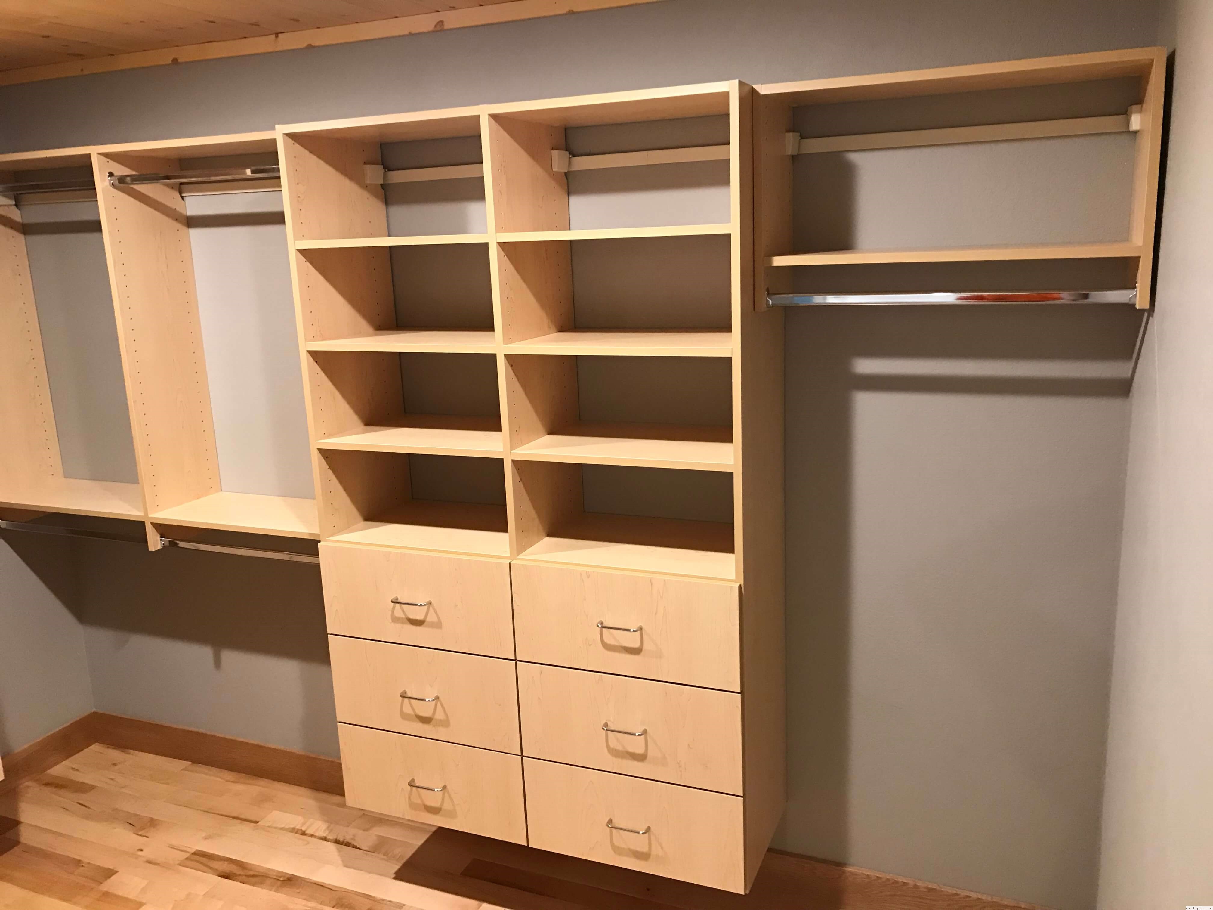 Custom closet with light wood drawers, open shelving, and double hanging rods in Green Bay, WI.