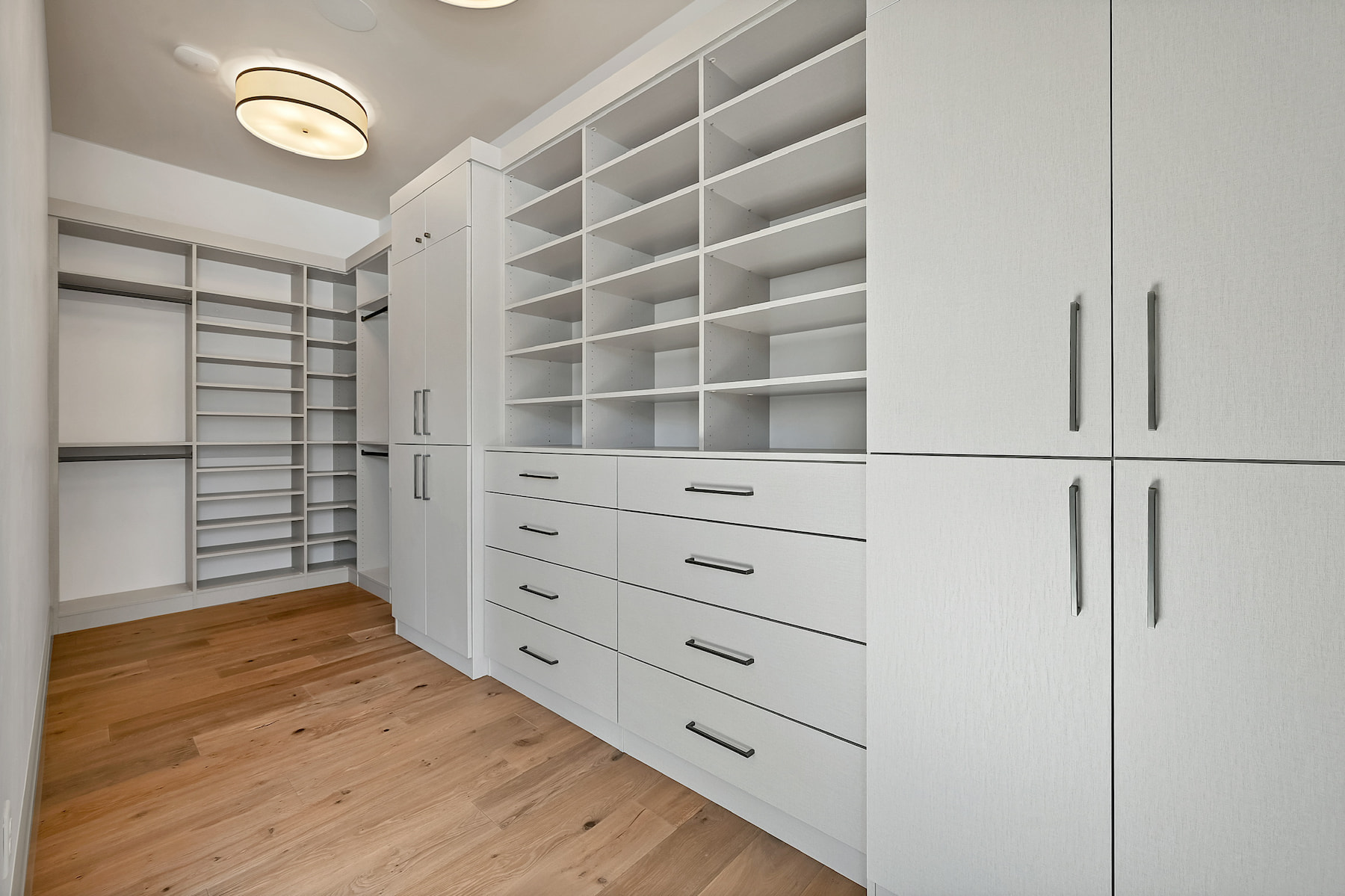 Luxury white closet with tall storage cabinets, multiple drawers, and extensive shelving.