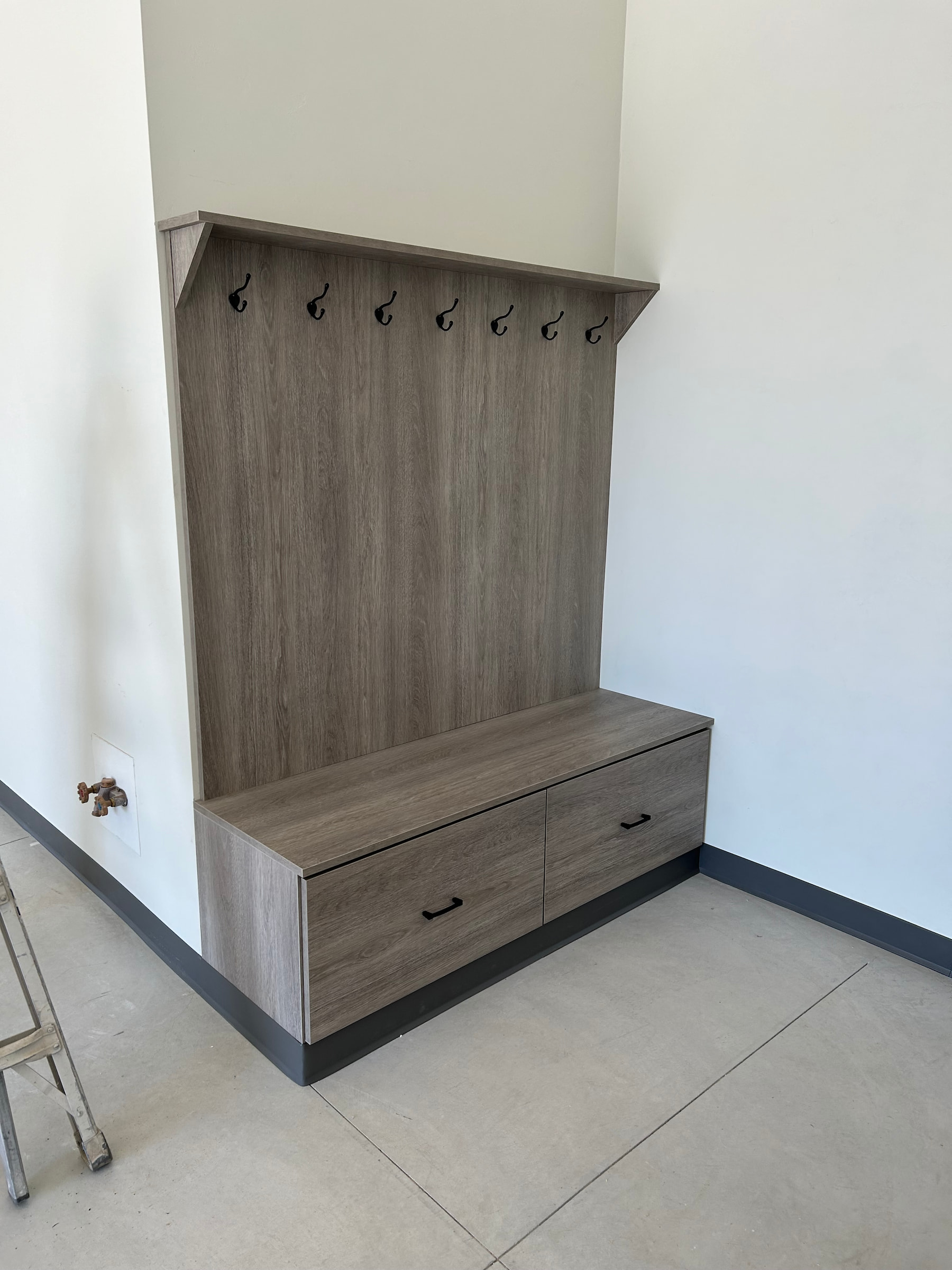 Woodgrain mudroom bench with built-in hooks and storage drawers in Wisconsin entryway.