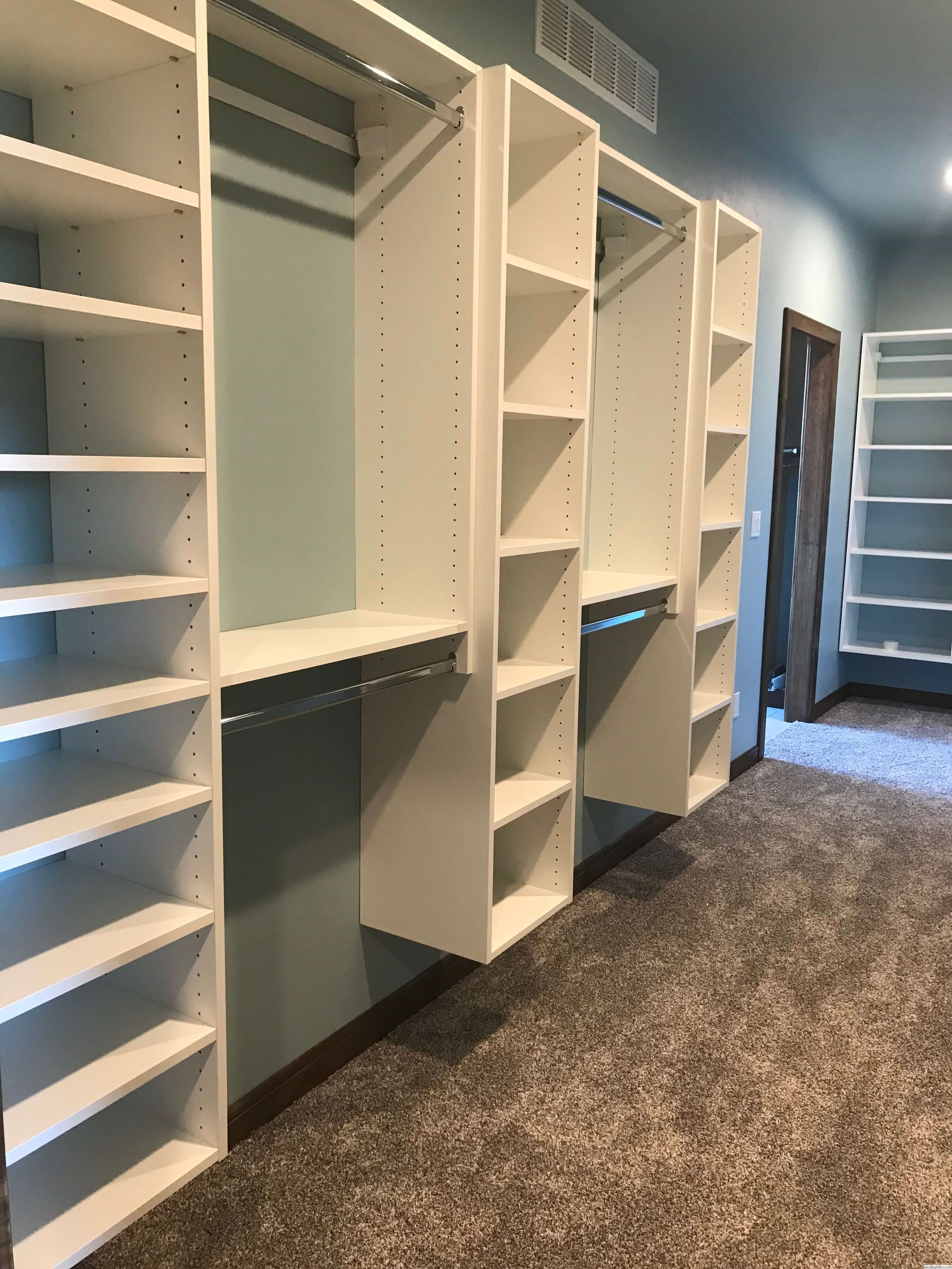Walk-in custom closet with double hanging rods, open shelving, and blue accent walls in Green Bay, WI.