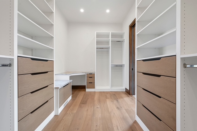 Spacious walk-in custom closet with built-in drawers, open shelving, and corner desk in Green Bay, WI.