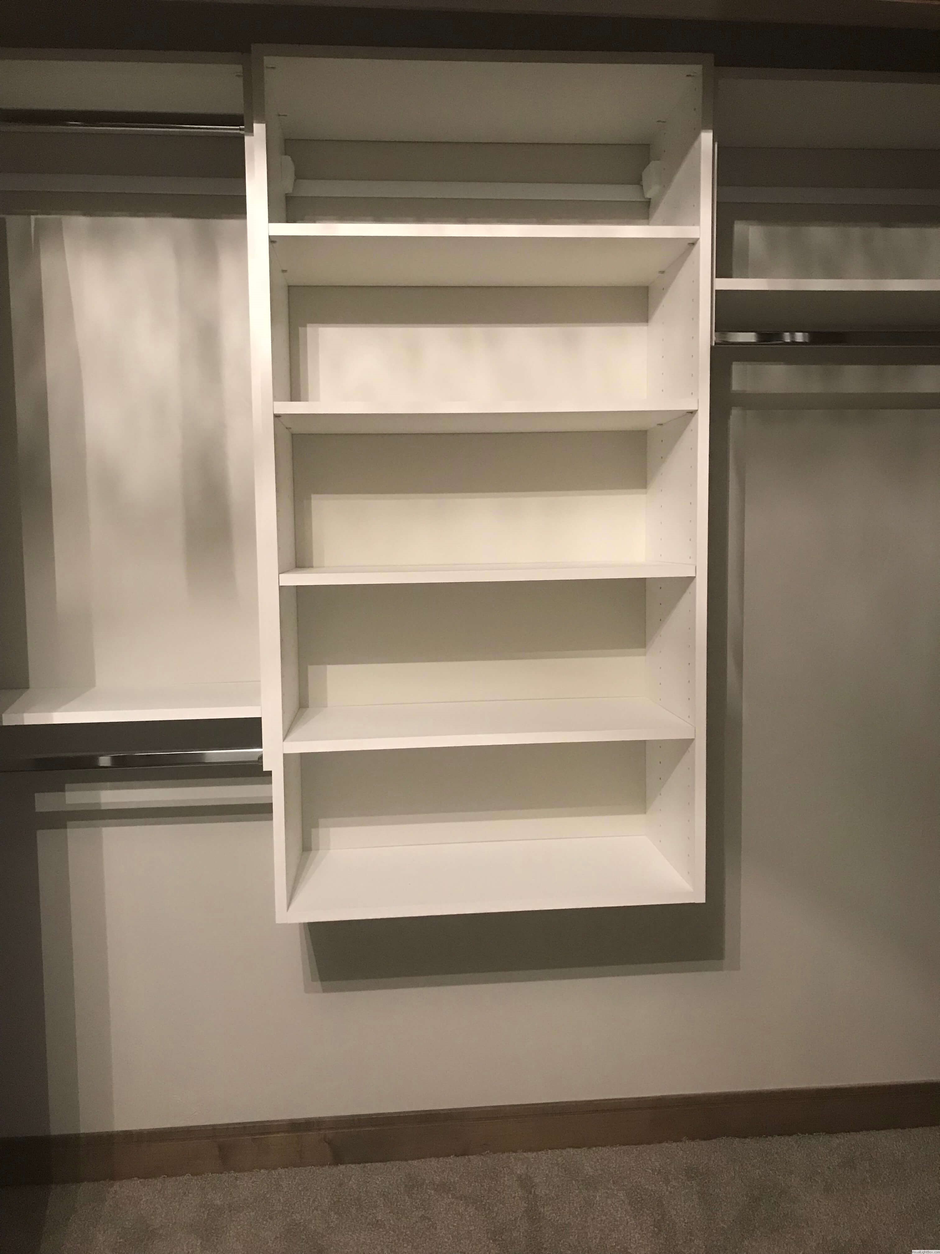 Custom walk-in closet with built-in drawers, open shelving, and pull-down hanging rods in Green Bay, WI.