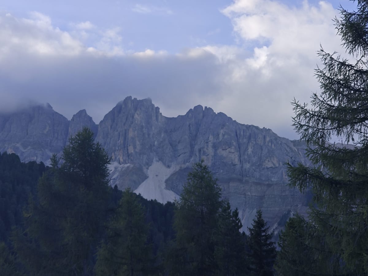 Early-morning light on a jagged Dolomite ridge above Misurina, larches in the foreground and a pale scree fan below the wall