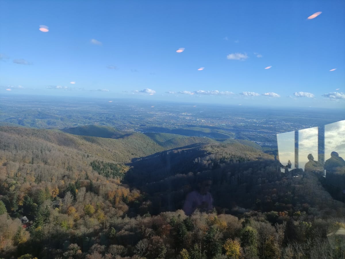 Zagreb spread across the plain seen through the glass of the TV tower's viewing deck, forested Medvednica foothills in between