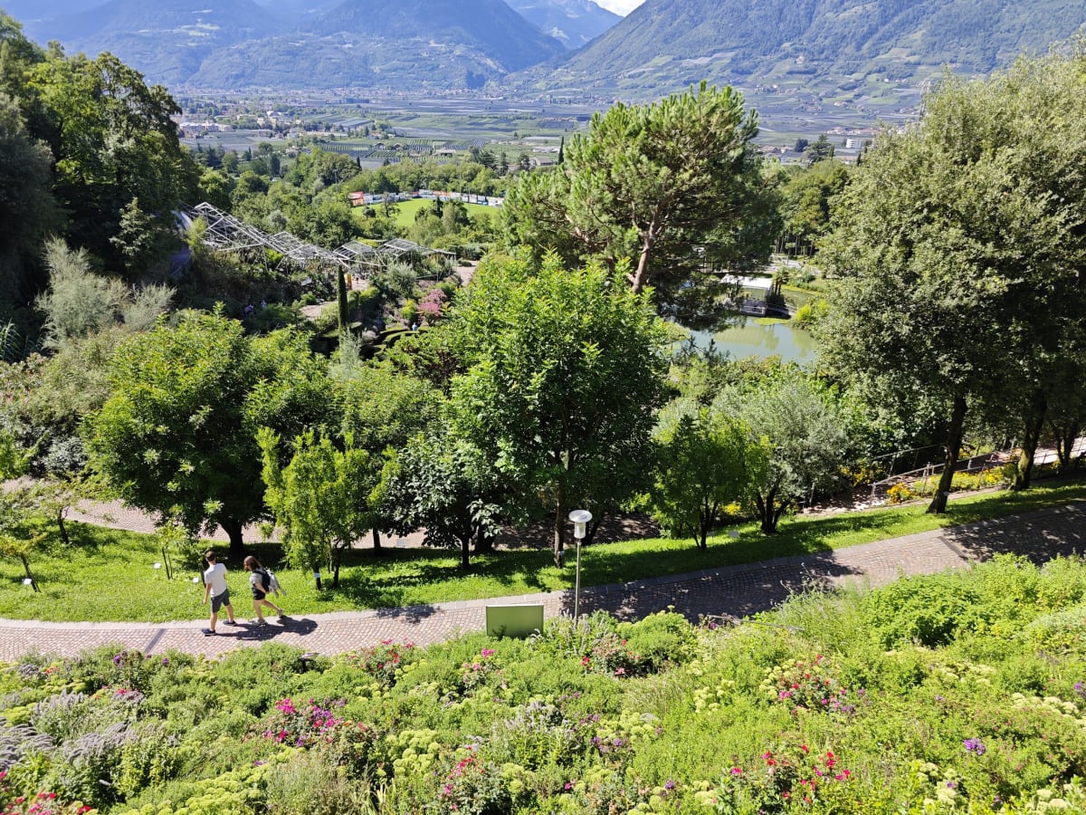 Winding paths and pergolas among trees and flower beds, with the Adige valley and mountains stretching away beyond the gardens