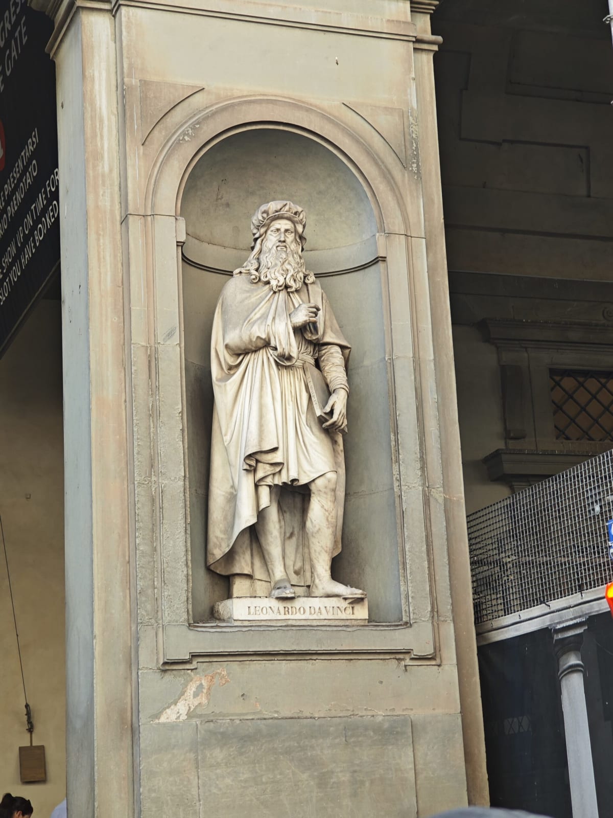 A marble statue of Leonardo da Vinci standing in a niche of the Uffizi colonnade